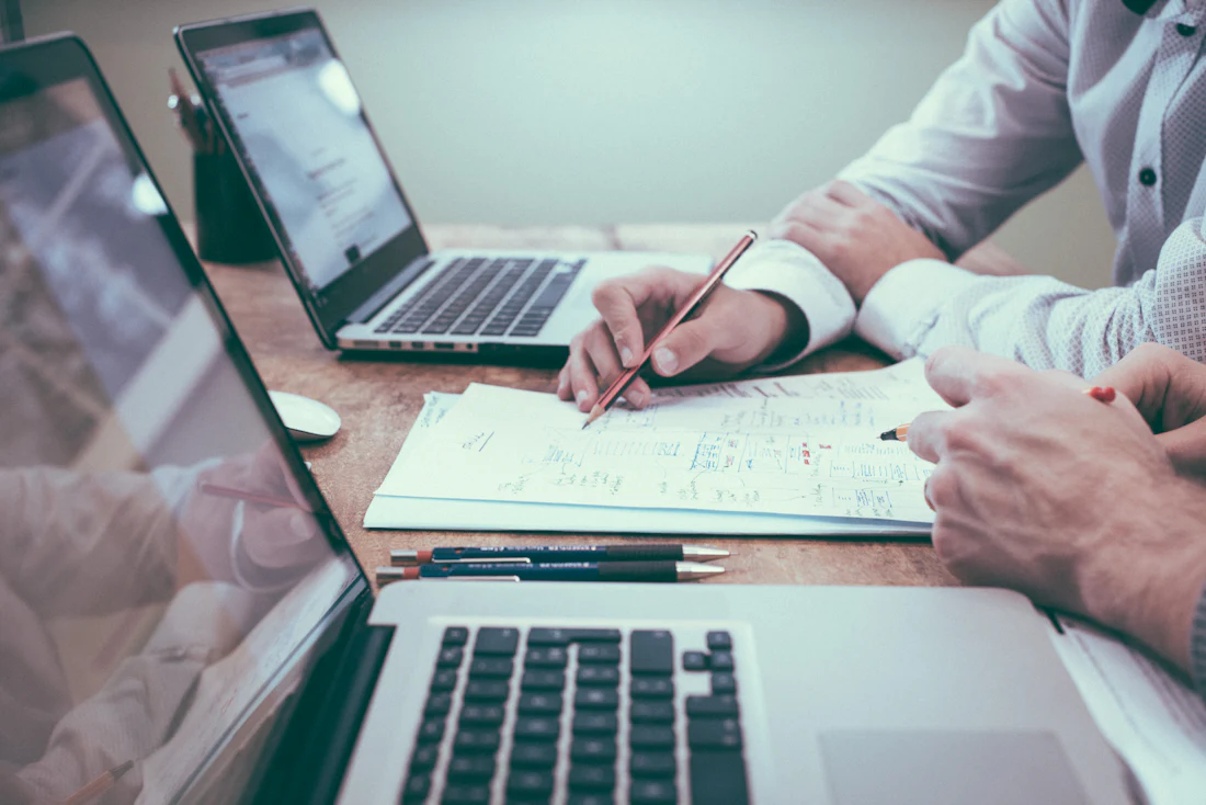 Two people working through a plan on paper next to their laptops