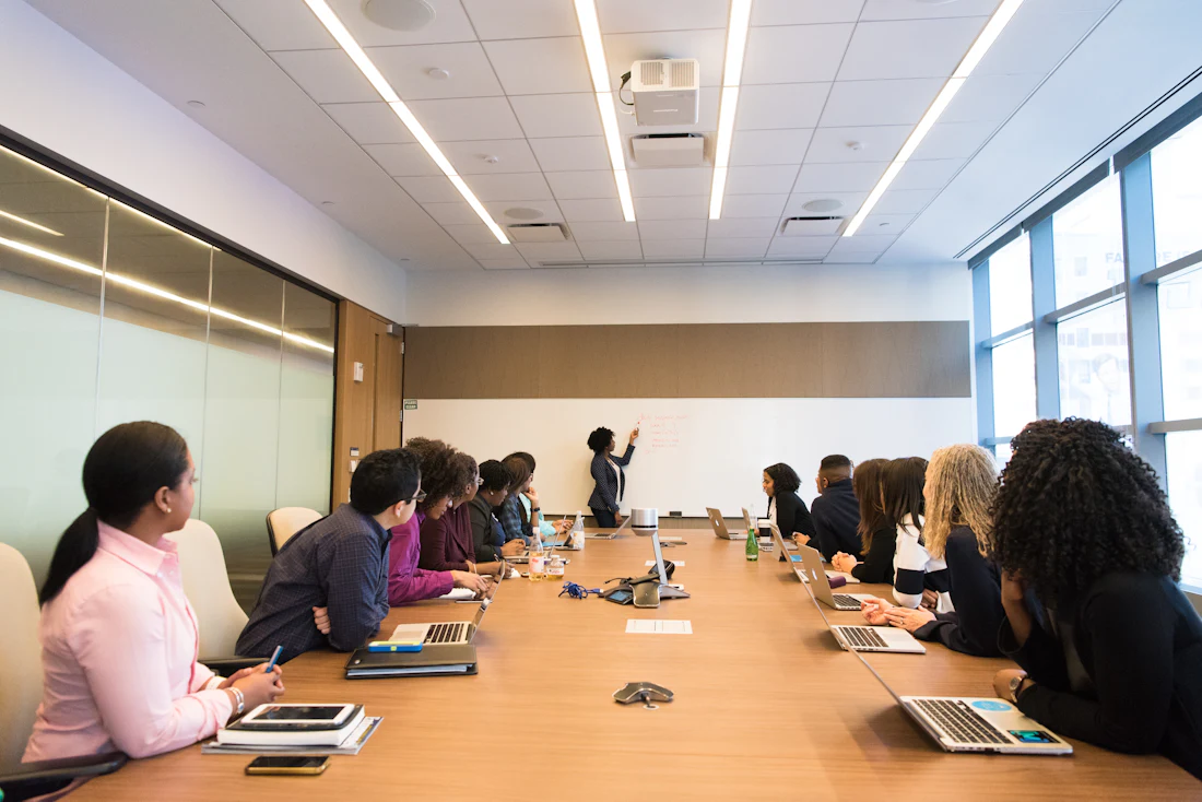 A sales team around a conference table, one colleague at the whiteboard